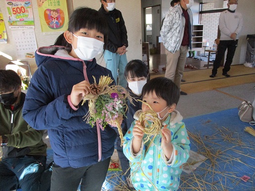 完成したわら飾りを手に持った女の子と小さな男の子の写真