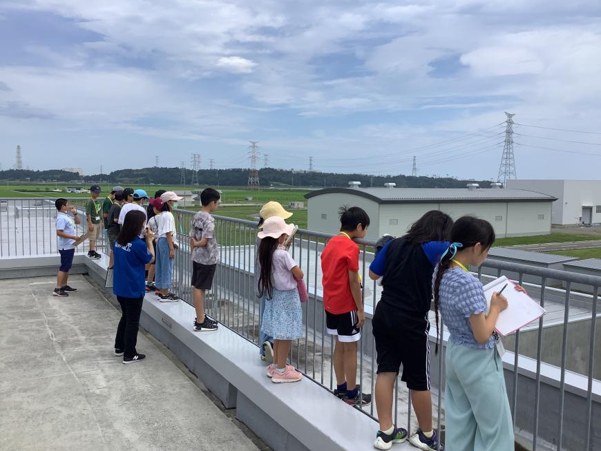 建物屋上のフェンス部分から遠くを眺めている子供達や、メモを取っている女の子の写真