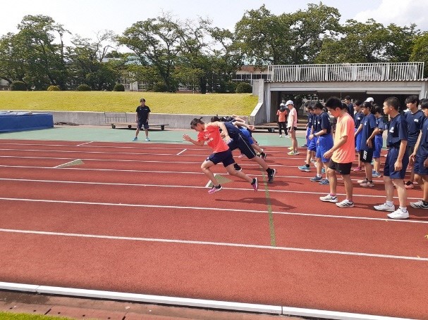 中学生たちが5列に並び、前の5人が走り出す様子を横から撮影した写真