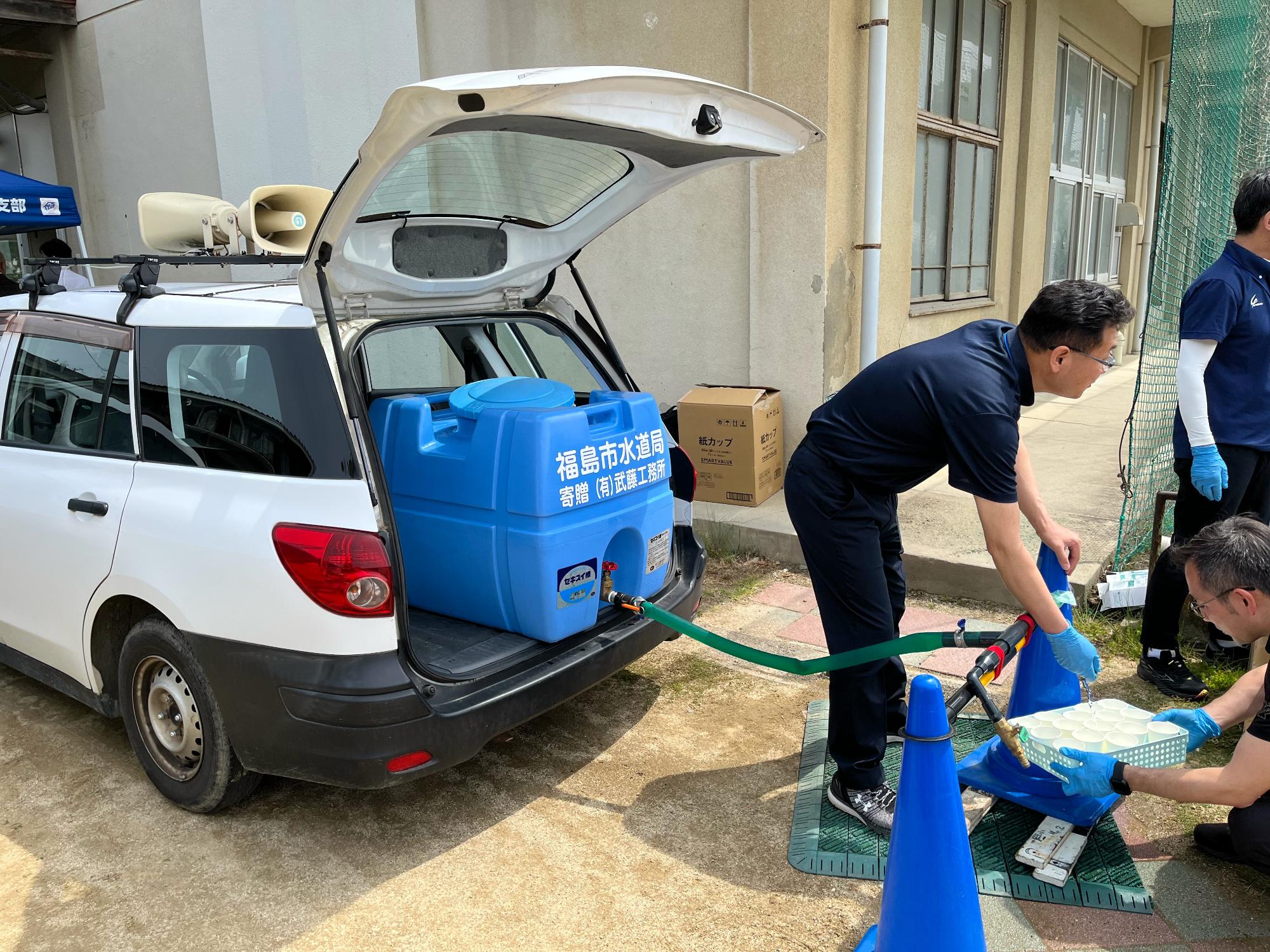 給水所でタンクから水を注ぐ