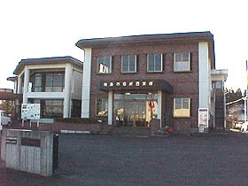 茶色の外壁と両側が白い外壁、2階建ての建物で中央に玄関があり右側に2階への外階段がある西支所の外観写真