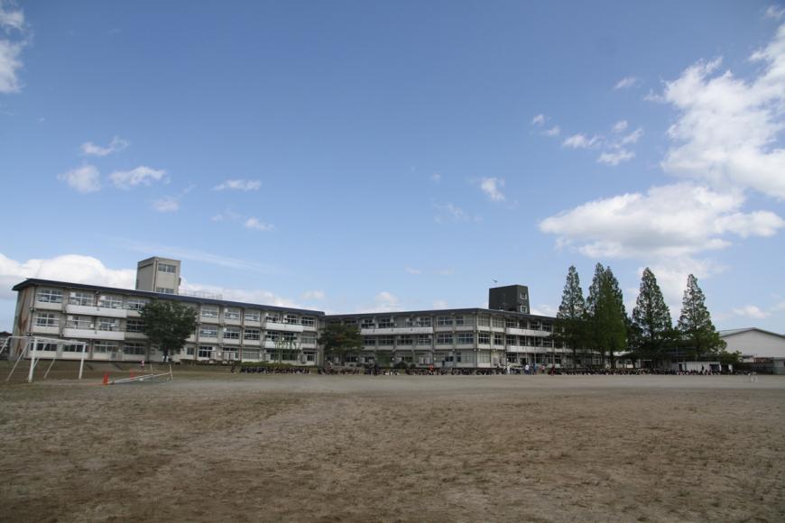 広いグラウンドの奥に3階建ての校舎が2棟並んだ蓬莱中学校の写真