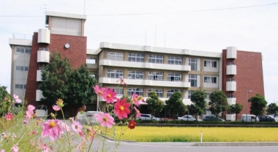 コスモスの花越しに撮影した4階建ての野田中学校の外観写真
