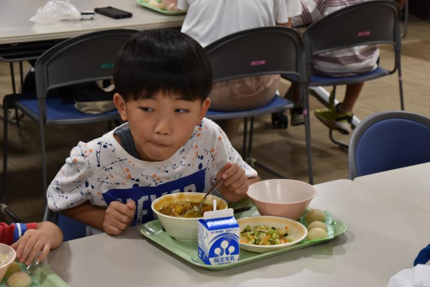 男の子がカレーを口の中いっぱいに入れながら食べる様子の写真