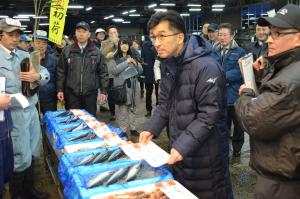 水産物が並べられた市場で、市長と関係者が初せりを行っている写真
