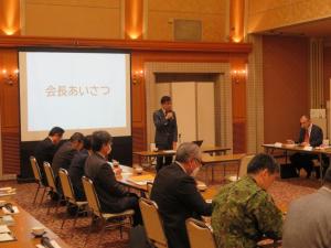防災会議の会場で「会長あいさつ」と表示されたスクリーンの前に立つ市長が挨拶を行っている様子の写真
