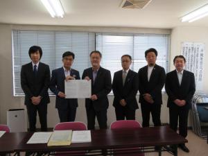 室内で市長を含む男性6名が横に並び、市長と男性で要望書を持っている写真