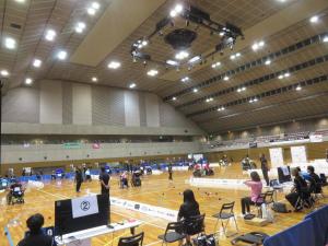 体育館の区切られたコート内でボッチャの試合が行われている写真