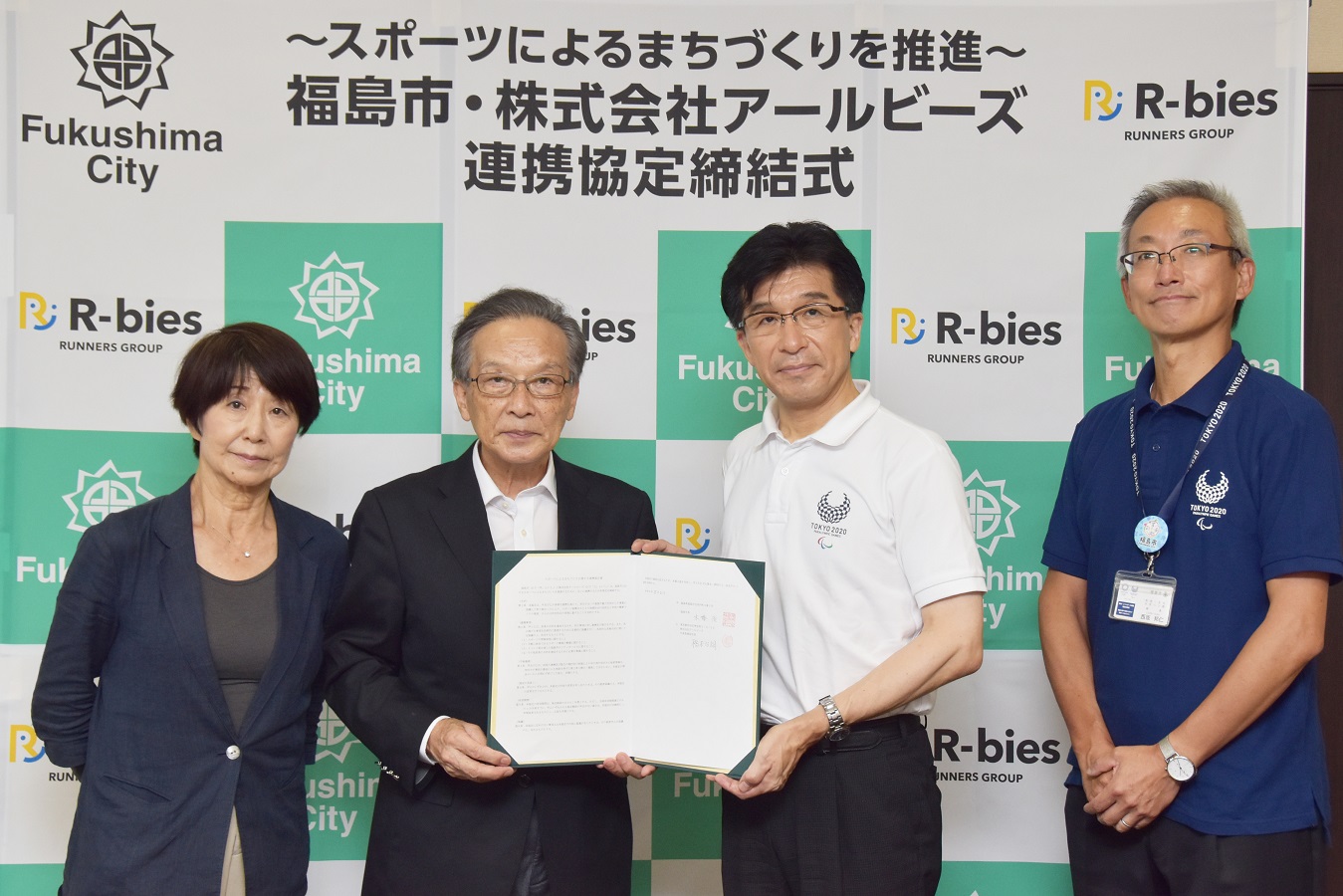 株式会社アールビーズの役員と市長が締結した書類を持ち撮影している写真