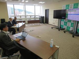 前方のモニター2台をみながら知事と会談をしている市長を横から写した写真