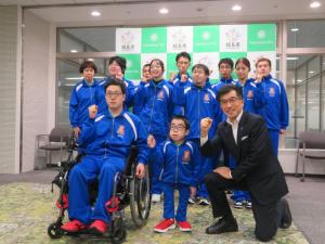 全国障がい者スポーツ大会へ出場する選手が青いジャージ姿でガッツポーズをして市長と記念撮影をしている写真