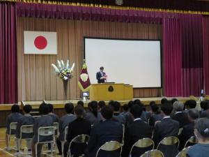 学校の体育館の舞台に立ち挨拶をしている市長の写真