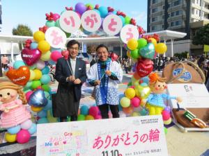 色とりどりの風船で作られた「ありがとう」のアーチの前で市長と関係者の人が並んで記念撮影をしている写真