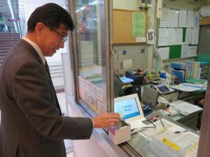 窓口の専用機で無料チケットを読み取らせている市長の写真