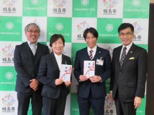 福島市のバックボードの前で男性2名に囲まれ、中央の男性と女性が激励金を持ちながら笑顔で記念撮影をしている写真