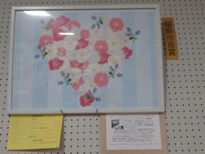 白い額に飾られた花でハートが描かれた作品の写真