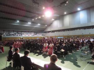 天井のライトに照らされ、大きな会場に設置された椅子に座った新成人の方々の写真