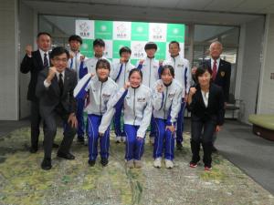 駅伝にでる参加者8名と関係者4名の人たちがガッツポーズをして記念撮影をしている写真