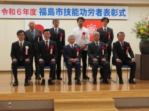 令和6年度福島市技能功労者表彰式で表彰された方々と関係者9名で並んで記念撮影をしている写真
