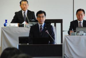 議会室で檀上に立つ市長が挨拶を行っている様子の写真