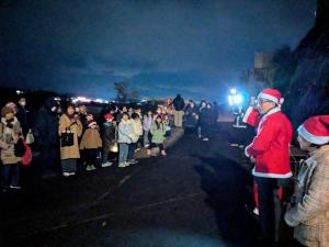 真っ赤なサンタの帽子と衣装をを着た市長が市民の前に立ち挨拶を行っている様子の写真