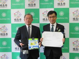 バックパネルの前で、清水町町会の代表の男性と協定書を広げて持つ市長が並んでいる写真