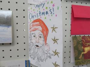 Merry Christmas!の文字とサンタクロースのイラストが描かれた紙をアップで撮影した写真