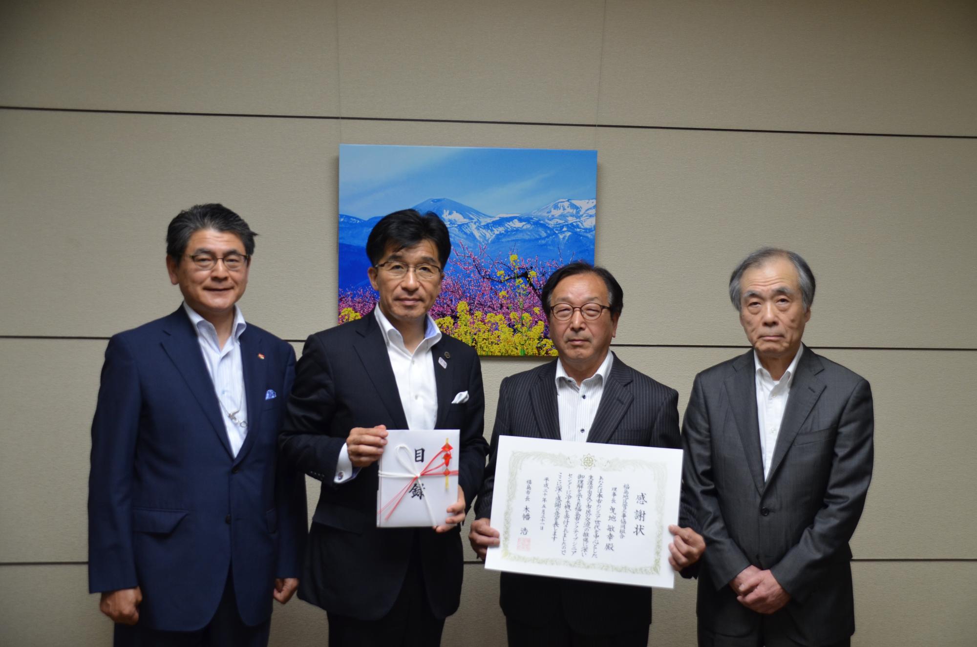 市長が目録を手に持ち、男性が賞状を手に持ち正面を向いている写真