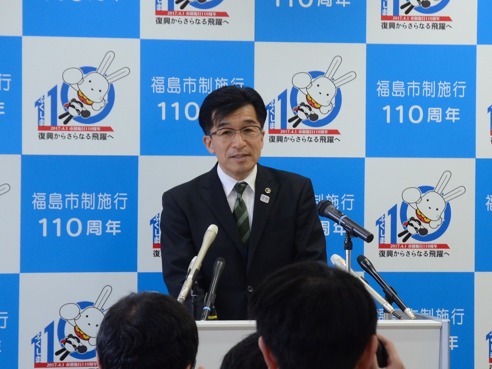 バックパネルの前で市長が演台で話をしている写真