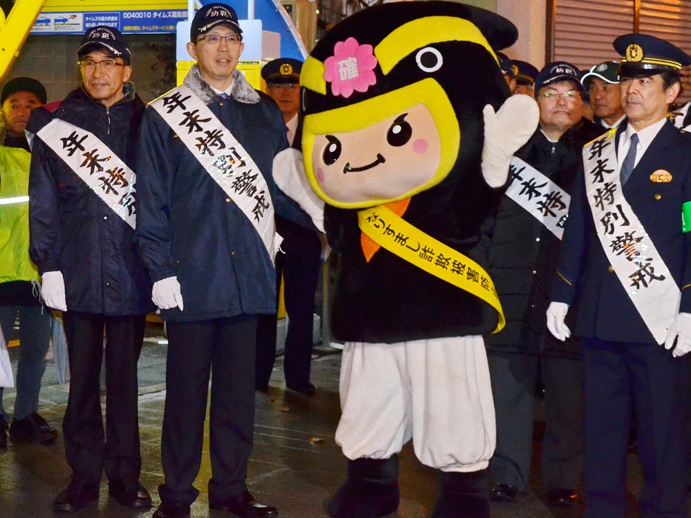 「年末特別警戒」と書かれた襷をかけた市長と関係者の方々とマスコットが集合して撮影した写真
