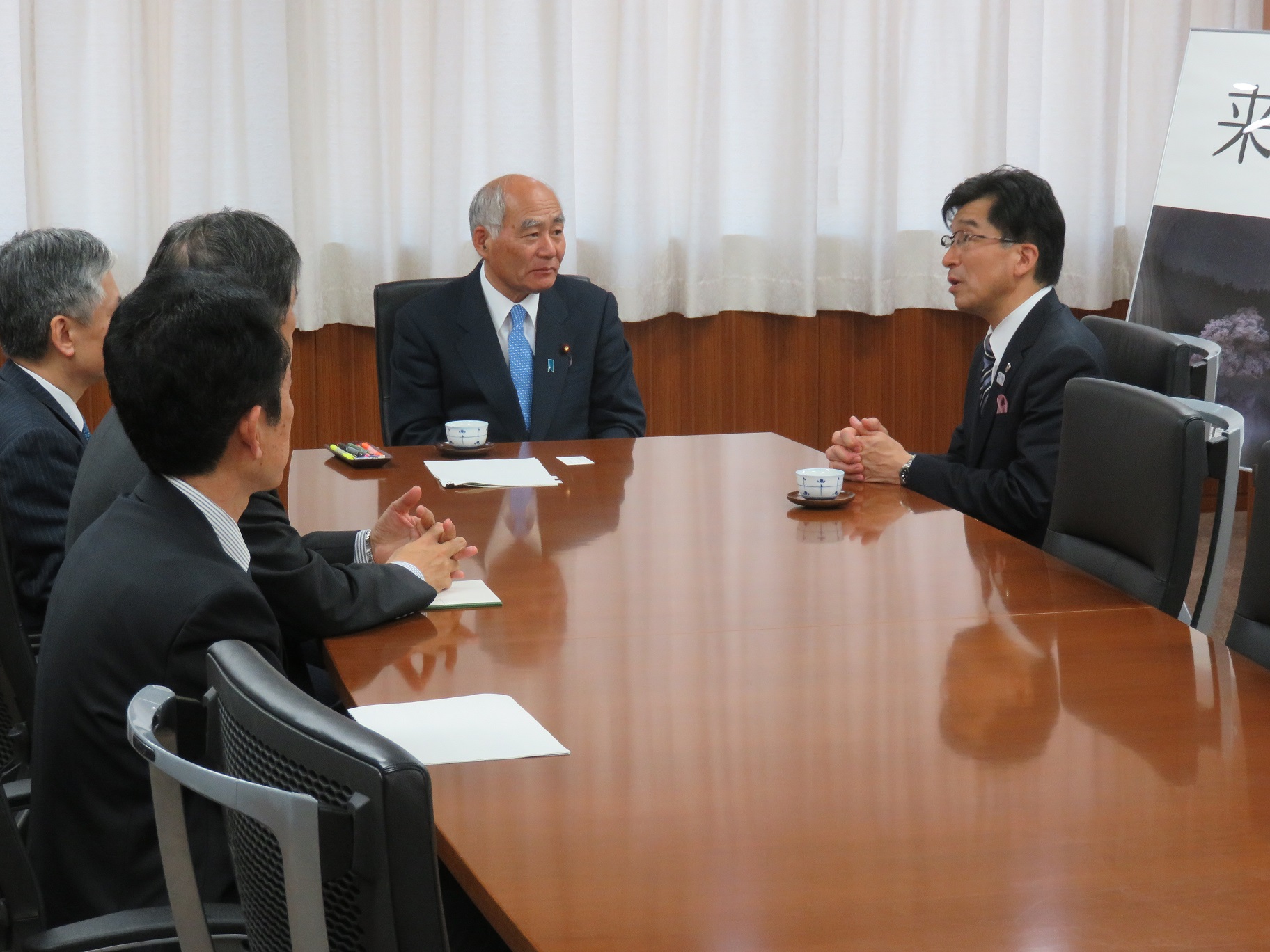 市長が長机に沿って座っている男性4名に向かって話をしている写真