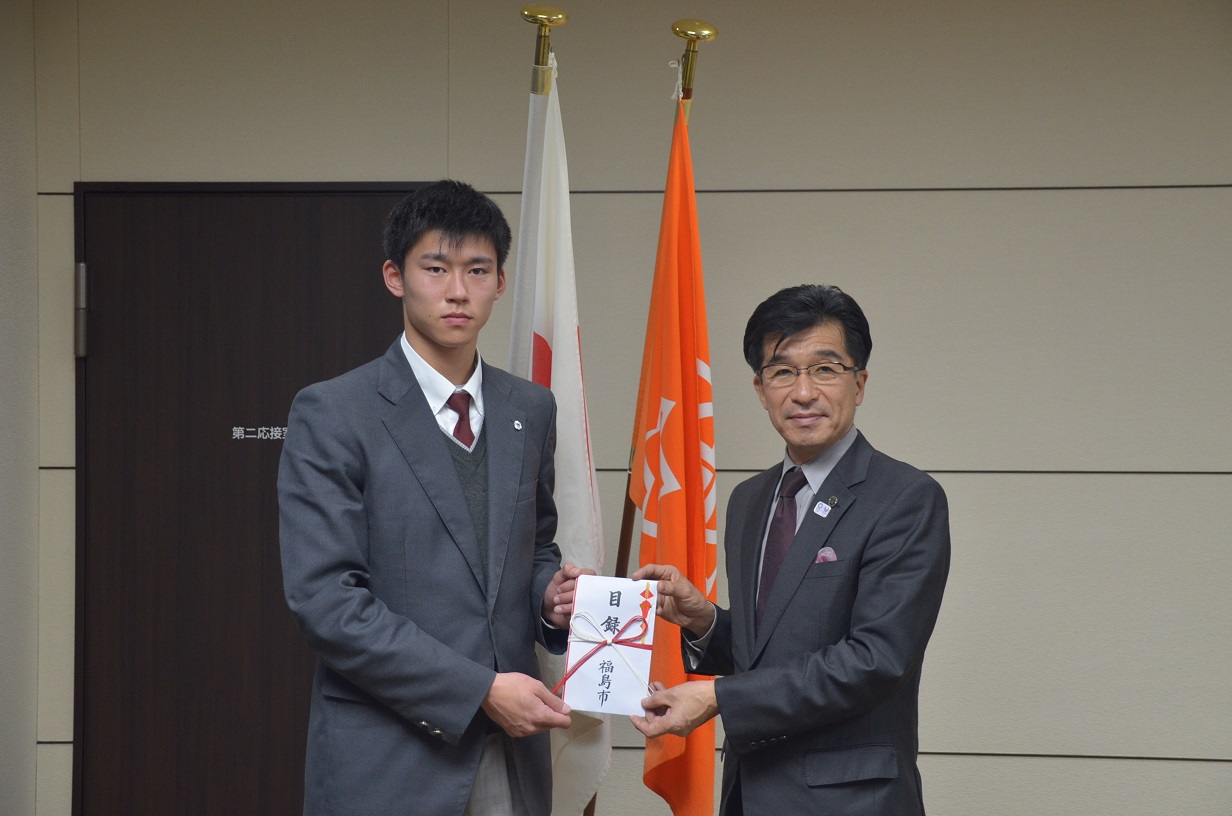 制服姿の生徒と市長で1つの目録を持ち、立っている写真