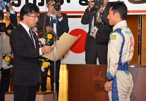 市長が室屋義秀さんに向けて賞状を読み上げている様子の写真