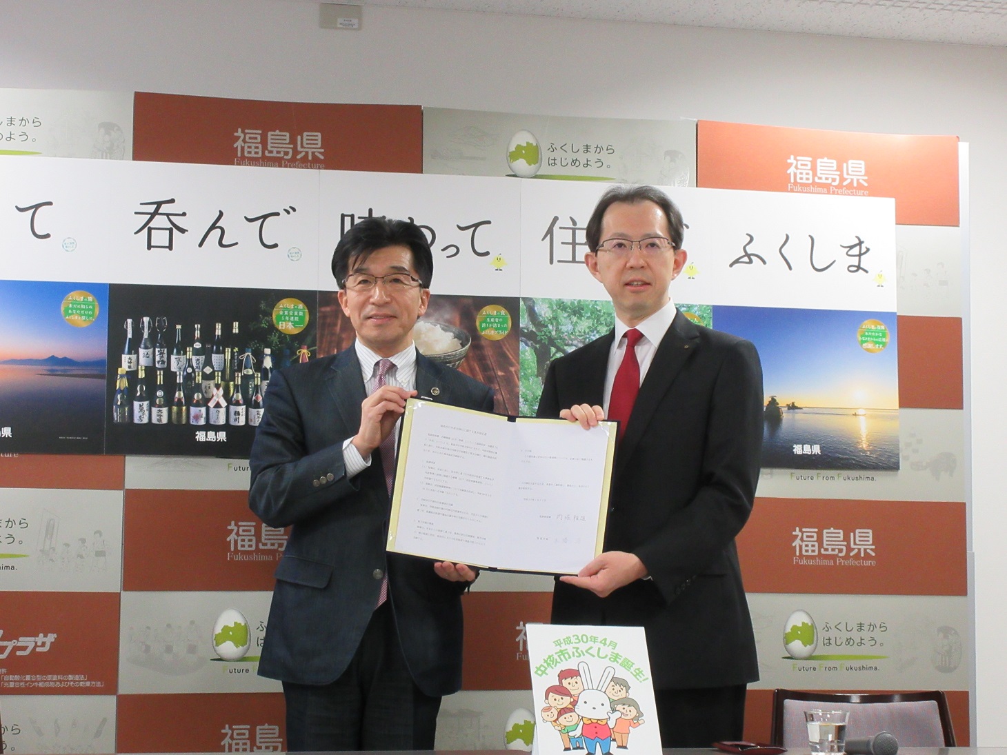 福島市のバックパネルの前で、福島県知事と福島市市長が、協定書を二人で手に持っている写真