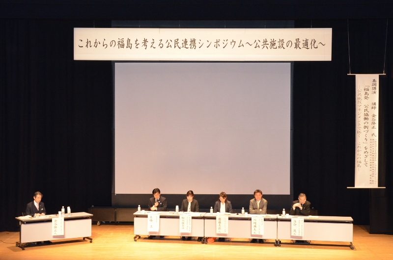 「これからの福島を考える公民連携シンポジウム~公共施設の最適化~」の吊りパネルあがあるステージ上で、市長と関係者がパネルディスカッションを行っている写真