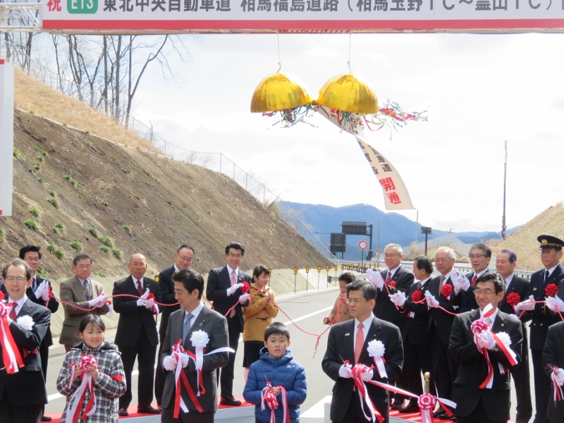 市長と、内堀県知事、安倍首相、石井国交大臣と子供たちが道路でテープカットをしている写真