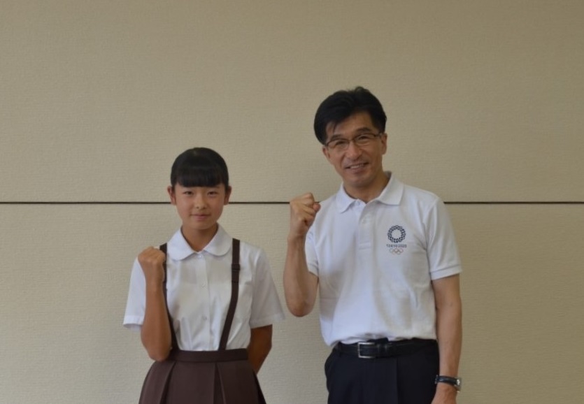 全国小学生陸上競技大会に出場する二瓶さんと市長が握りこぶしでポーズを取っている写真