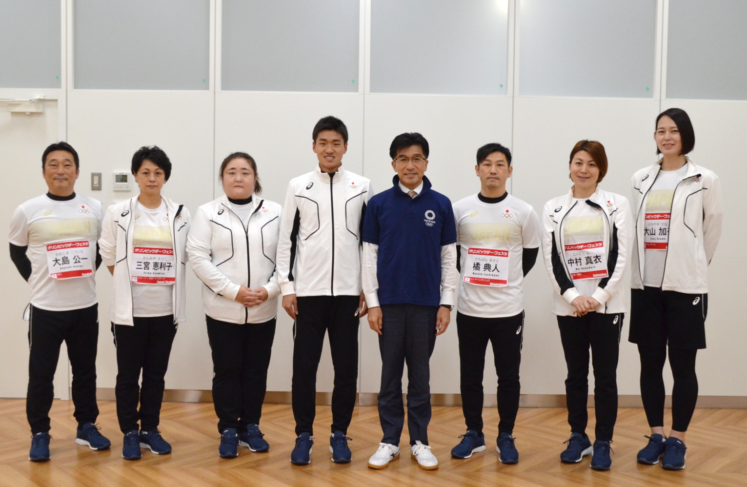 市長とトレーニングウエア姿の男性女性のオリンピアンの選手7人が横一列に並んでいる写真