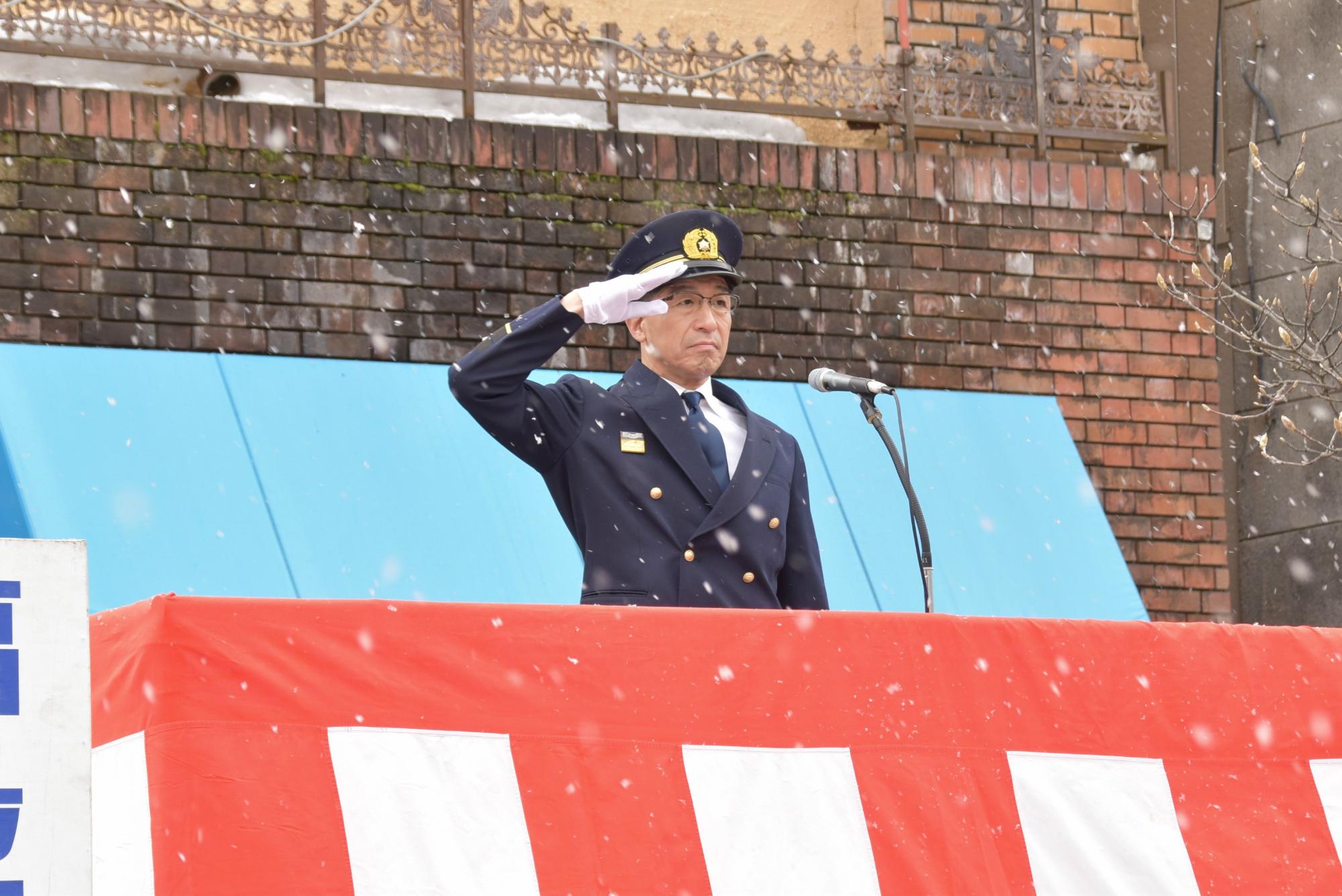 雪が舞う中、制服を着た市長が、敬礼をしている写真