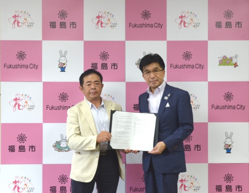 福島市のバックボードの前で福島建設ユニオン宍戸委員長と市長が協定書を一緒に持ち記念撮影している写真