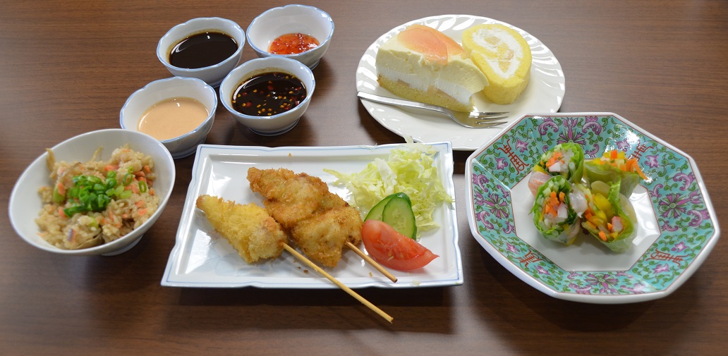 生徒が育てた食材を使った4種類の小鉢に入ったたれやケーキ、炊き込みご飯、串カツ、生春巻きがそれぞれお皿に盛りつけられたおもてなし料理の写真