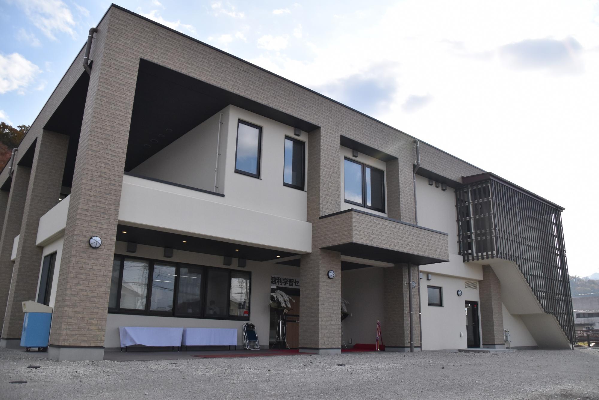 2階建ての鉄筋コンクリート造りの四角い建物で、茶色とベージュを基調とした新渡利学習センターの外観写真