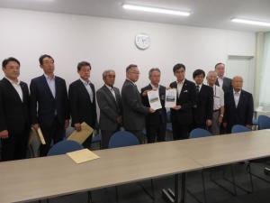 市長を含めて10名ほどの男性が横一列に並び、中心にいる市長を含めた3名で要望書を持っている写真