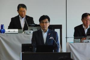 後方で座ってい男性が見ている中、演台に市長が立って話をしている写真
