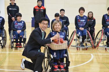 市長が、かごに入ったりんごをU-25女子車いすバスケ日本代表の選手へ手渡している写真