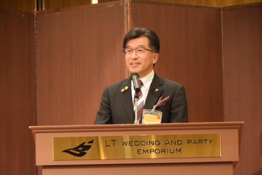 市長がプレートが貼ってある演台で話をしている写真