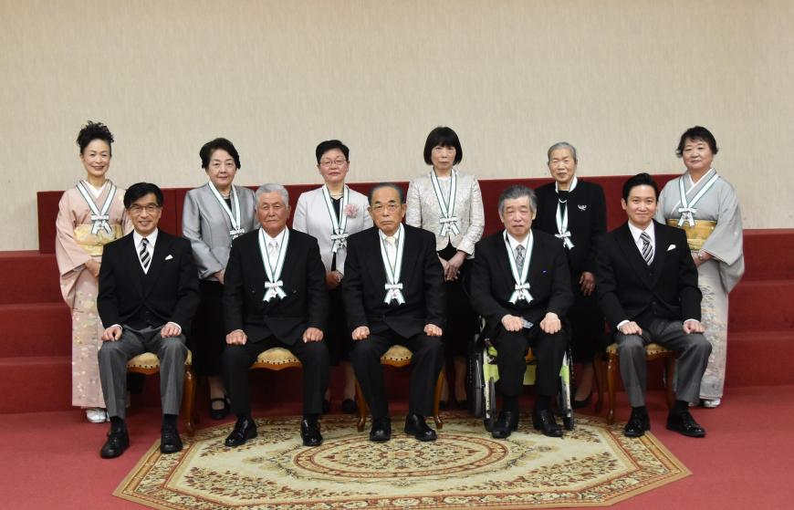 前列に市長とメダルをかけた男性3人が座り、後列にメダルをかけた女性6人が立って撮影した写真
