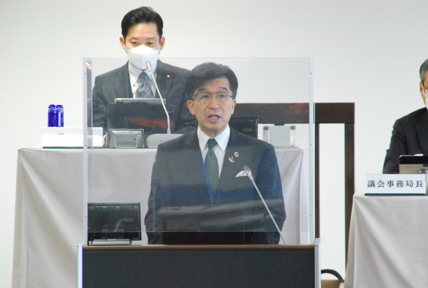 市長が議長と事務局長が見ている前で、演台に立ち話をしている写真
