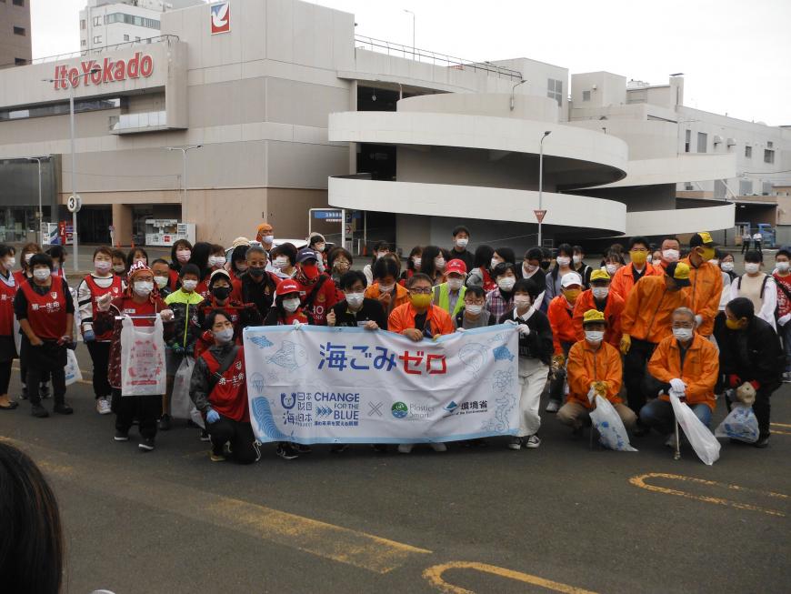 清掃活動に参加して人が集まり、前列の人が「海ごみゼロ」の横断幕を持っている集合写真