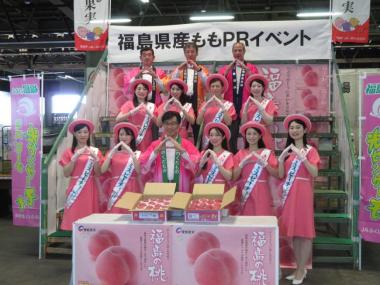 法被を着た市長を先頭にして他男性3名、ピンクの帽子と同色のワンピースを着た9名の女性が3段に分かれて整列し、指先を合わせてポーズをとっている写真